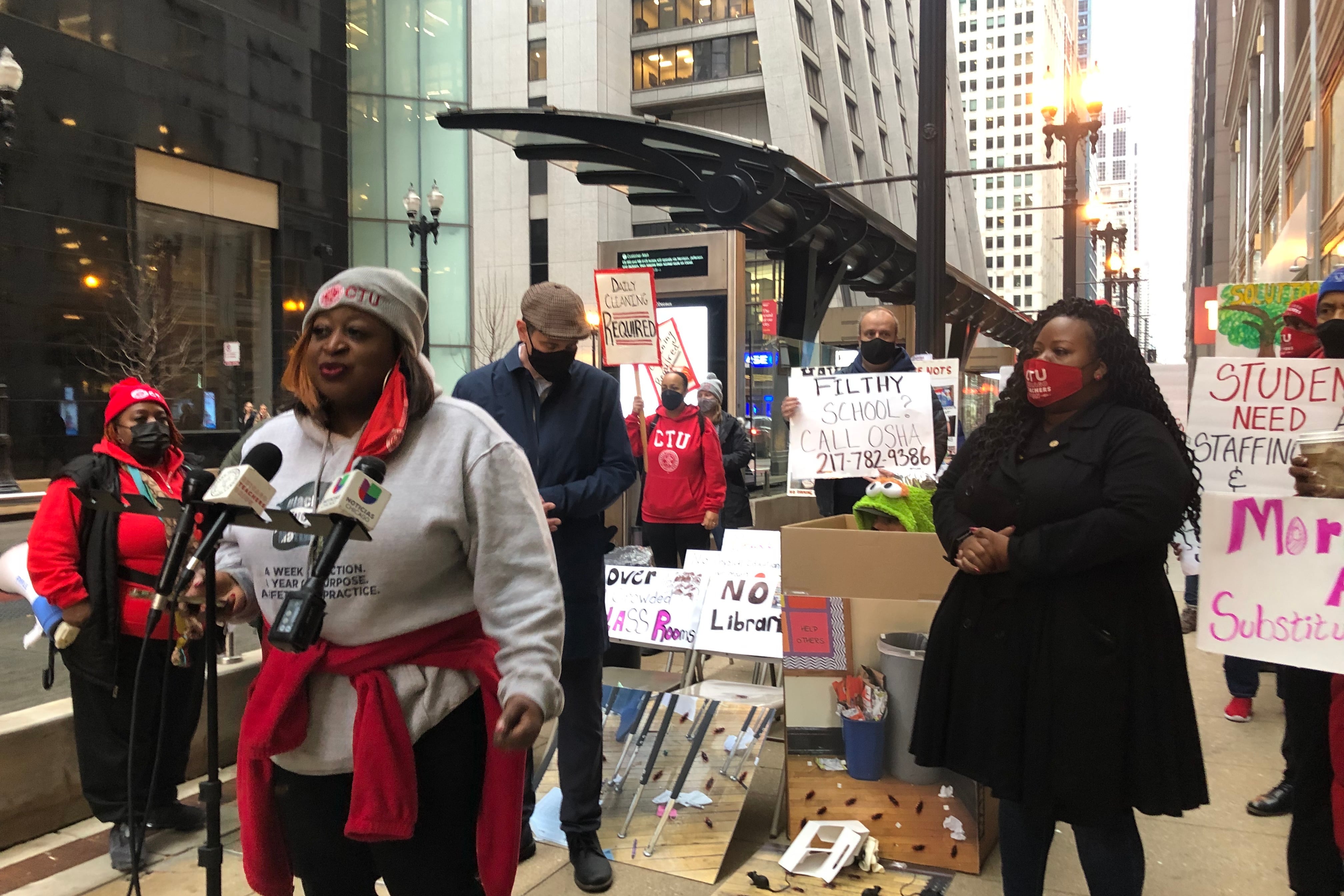 A woman at a microphone stand surrounded by members of the Chicago Teachers Union.
