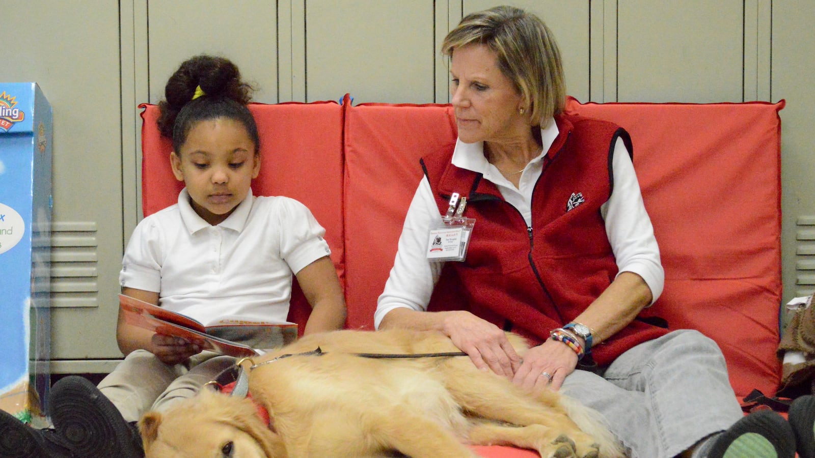Second-grader Aaleyah Stone reads aloud to Zoe, a therapy dog who visits Keystone Elementary School with her handler, Pam Westphal.