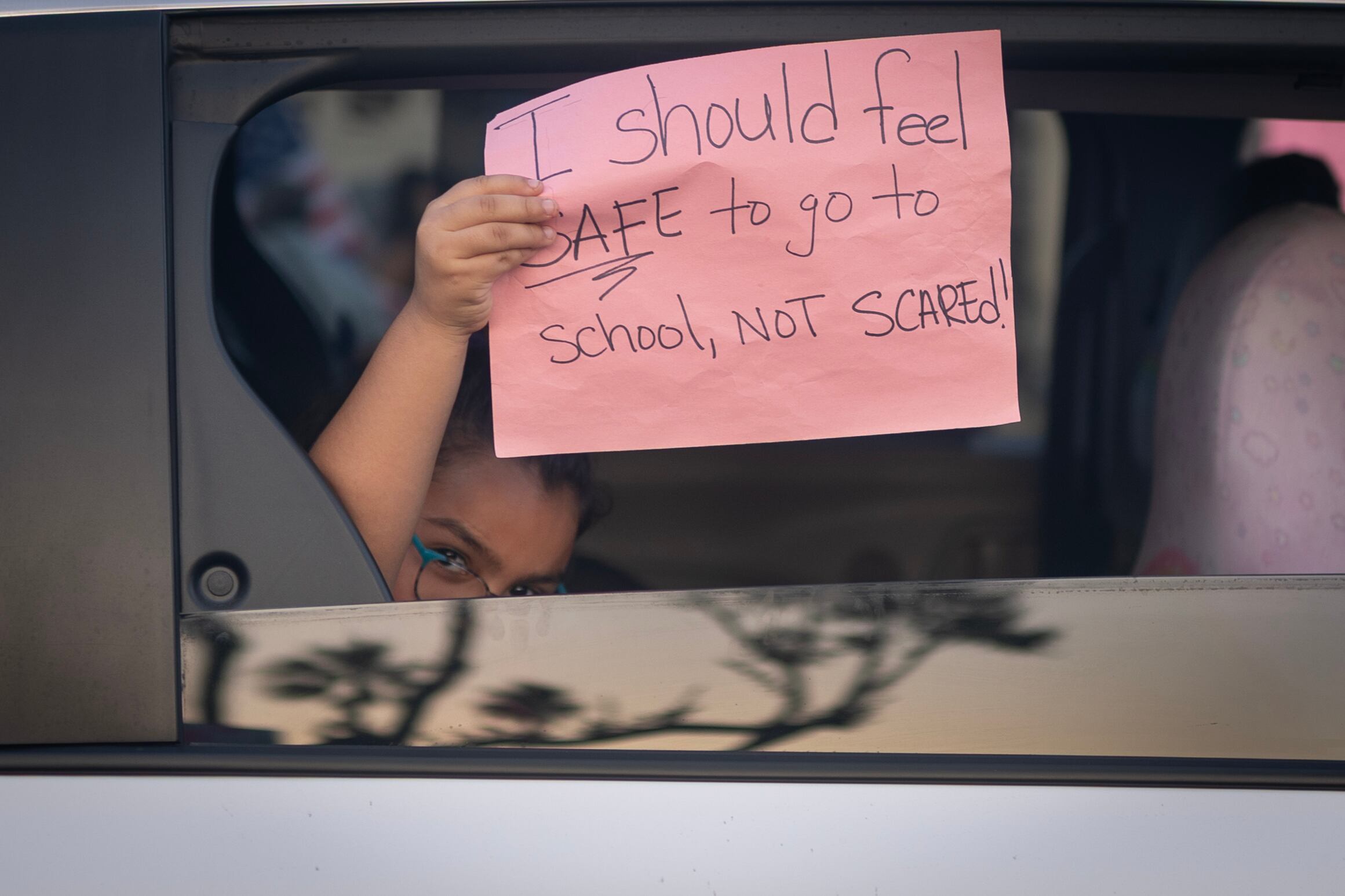 A pink protest sign is held up in a window.