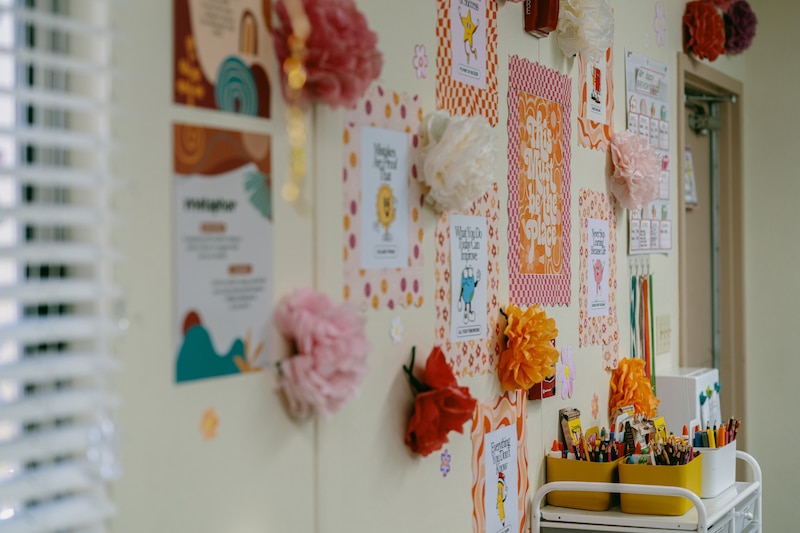 A photograph of a colorful wall full of posters and drawings and paper flowers.
