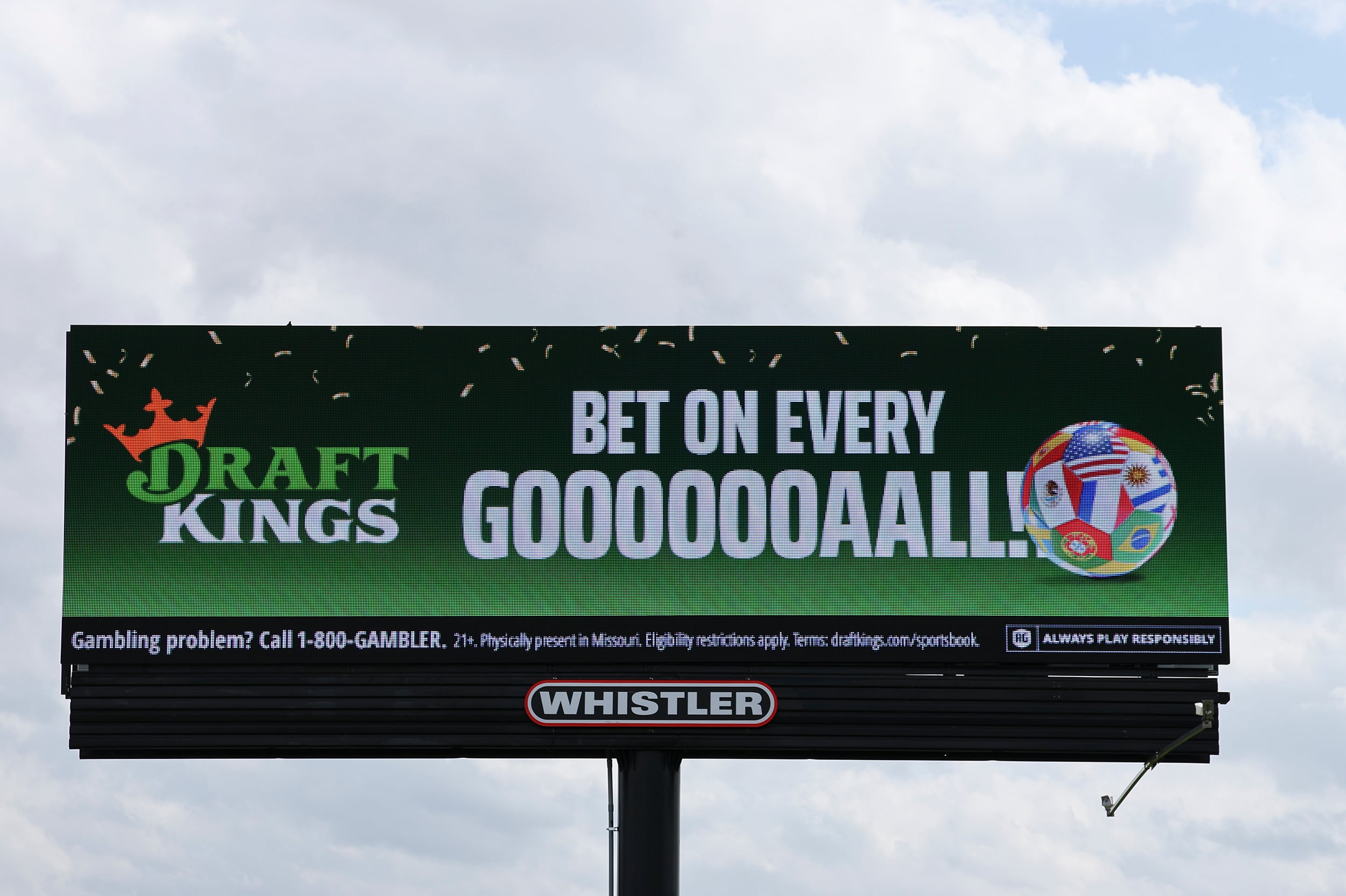 A large billboard with an ad for Draft Kings sports betting with a grey sky in the background.
