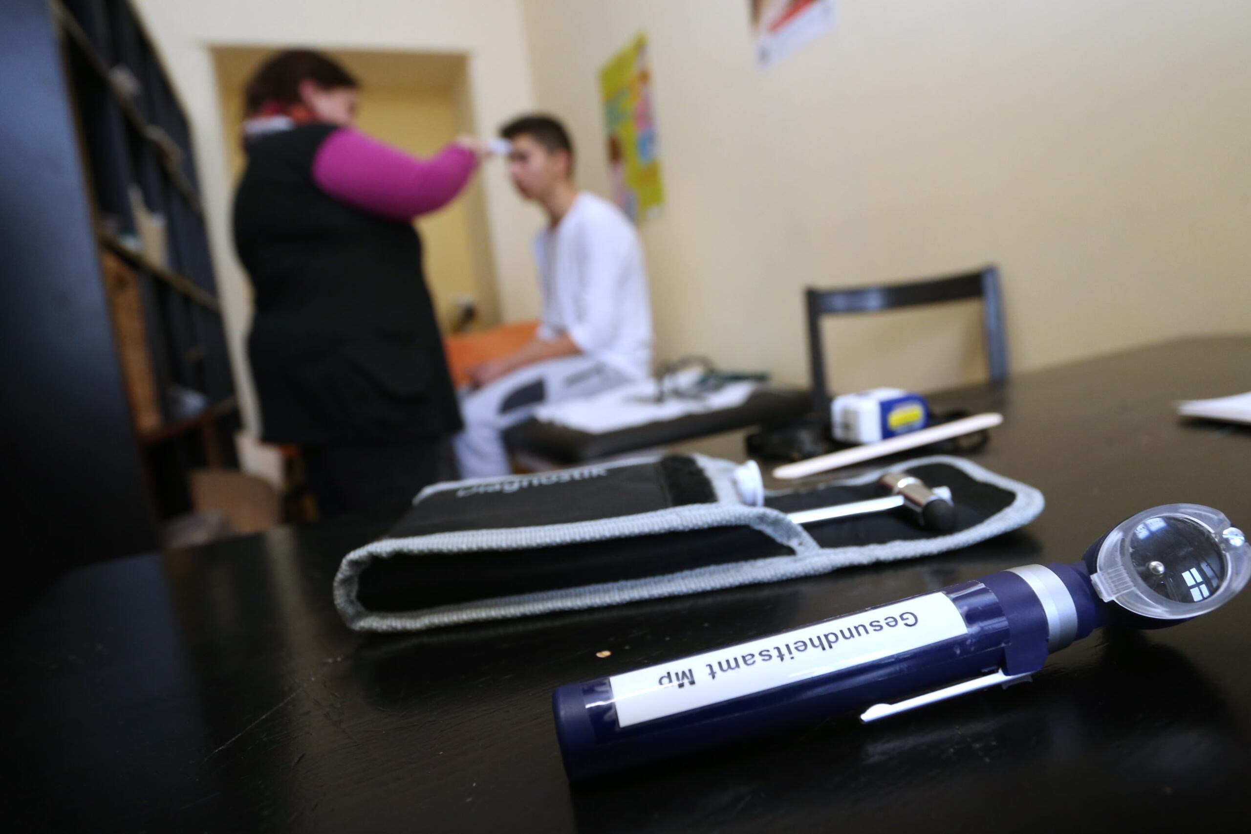 A school nurse and a student sit in the background while tools are seen in the foreground.