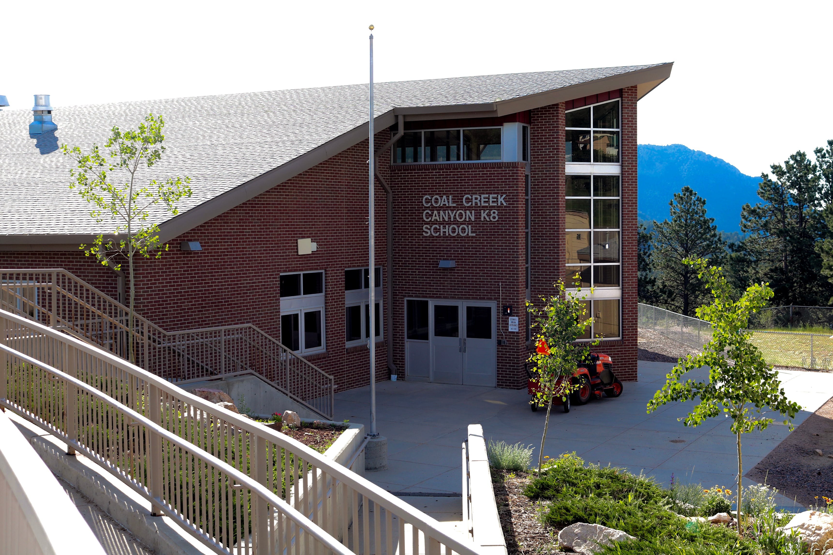 A brick school building with a flagpole in front.