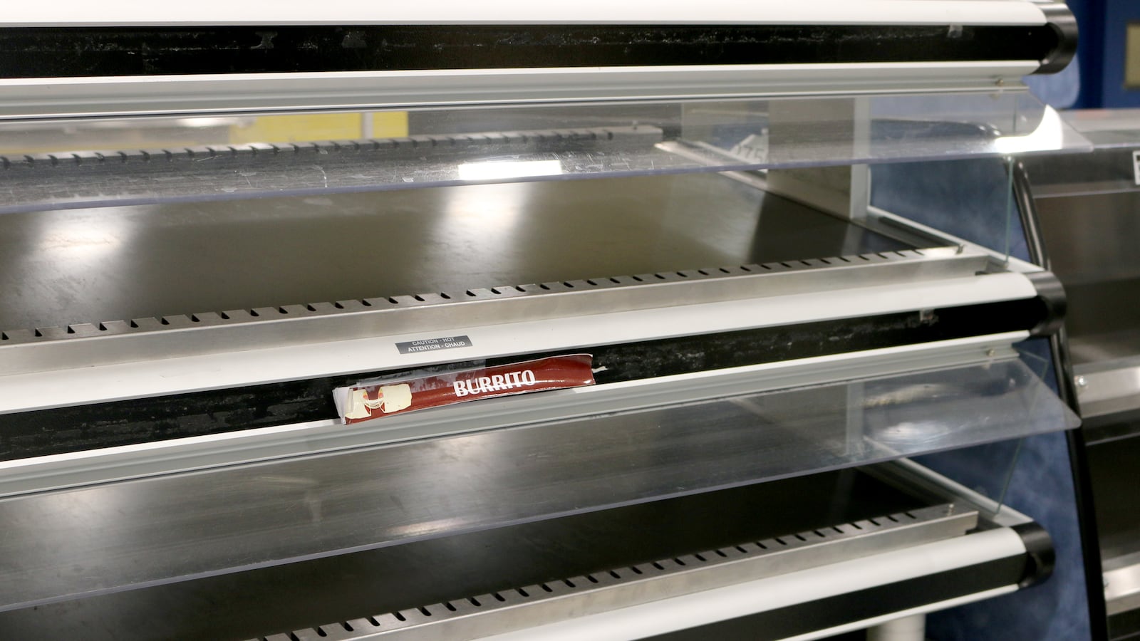 Two visible shelves in a hot food case that is completely empty.