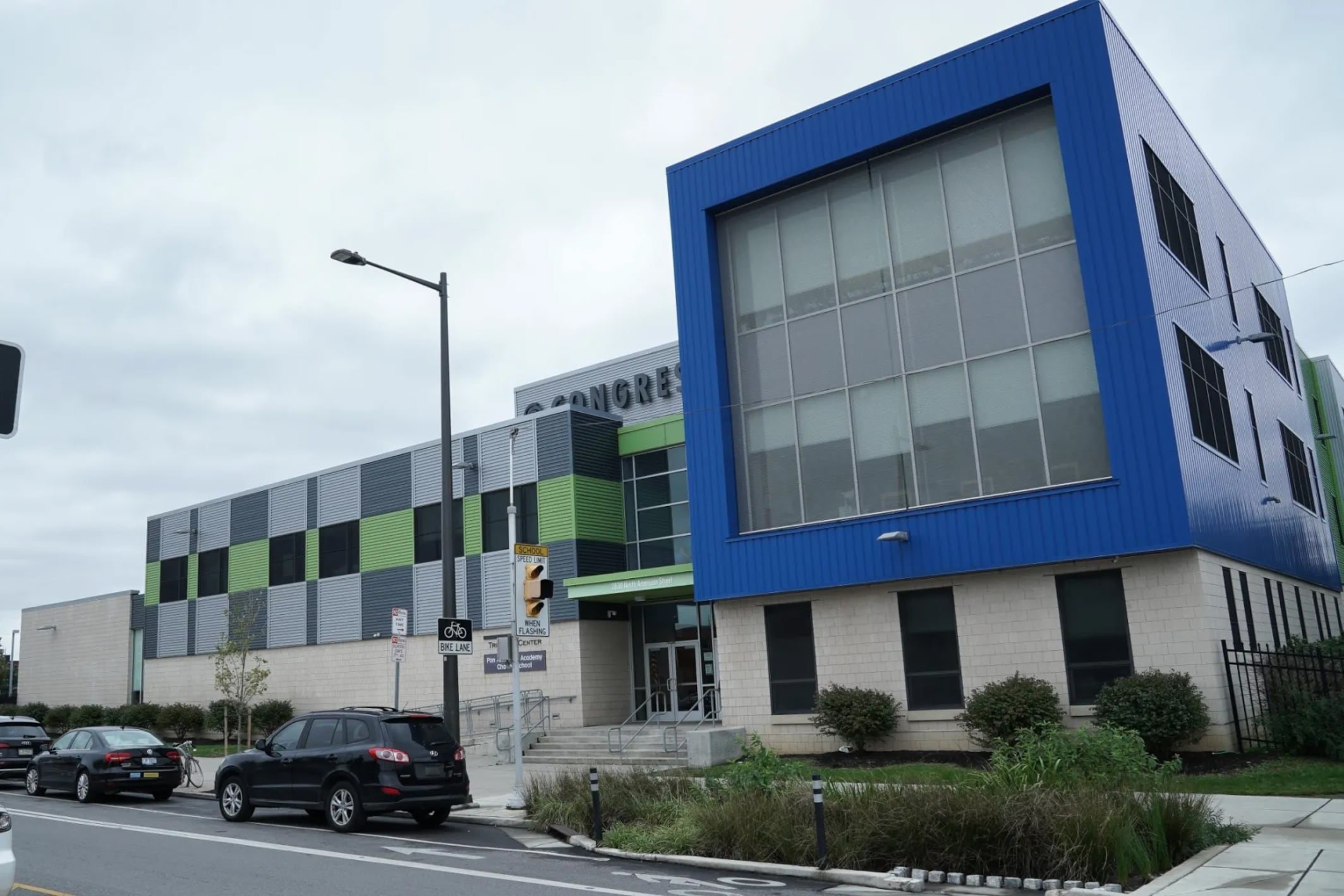 A white, blue and gray building near a street with cars parked out front.