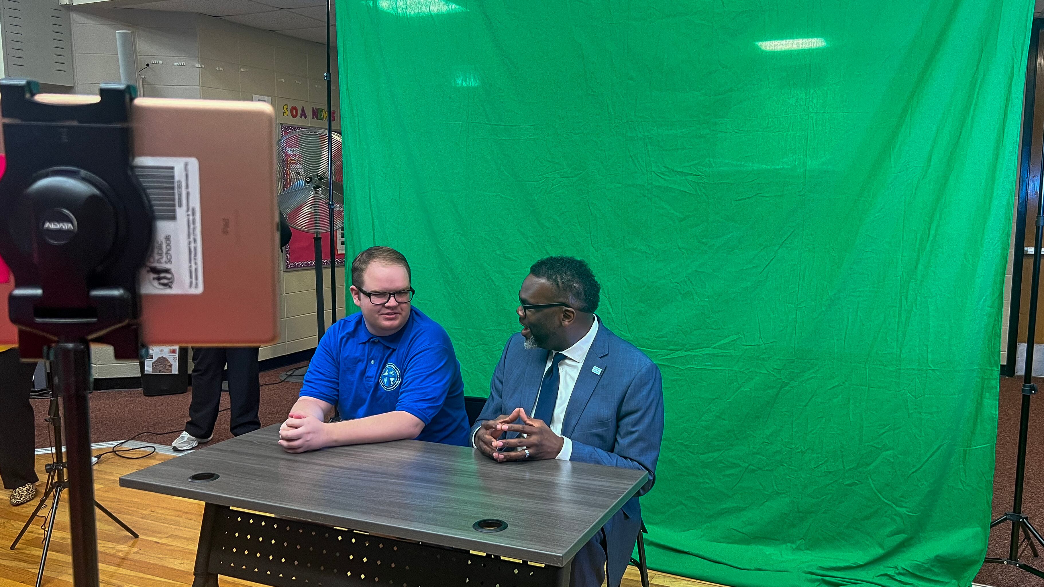 Mayor Brandon Johnson sits with Aidan Hughes at a mock broadcast studio at Southside Occupational Academy High School in Englewood. The school provides job training and life skills to older students with more challenging disabilities.