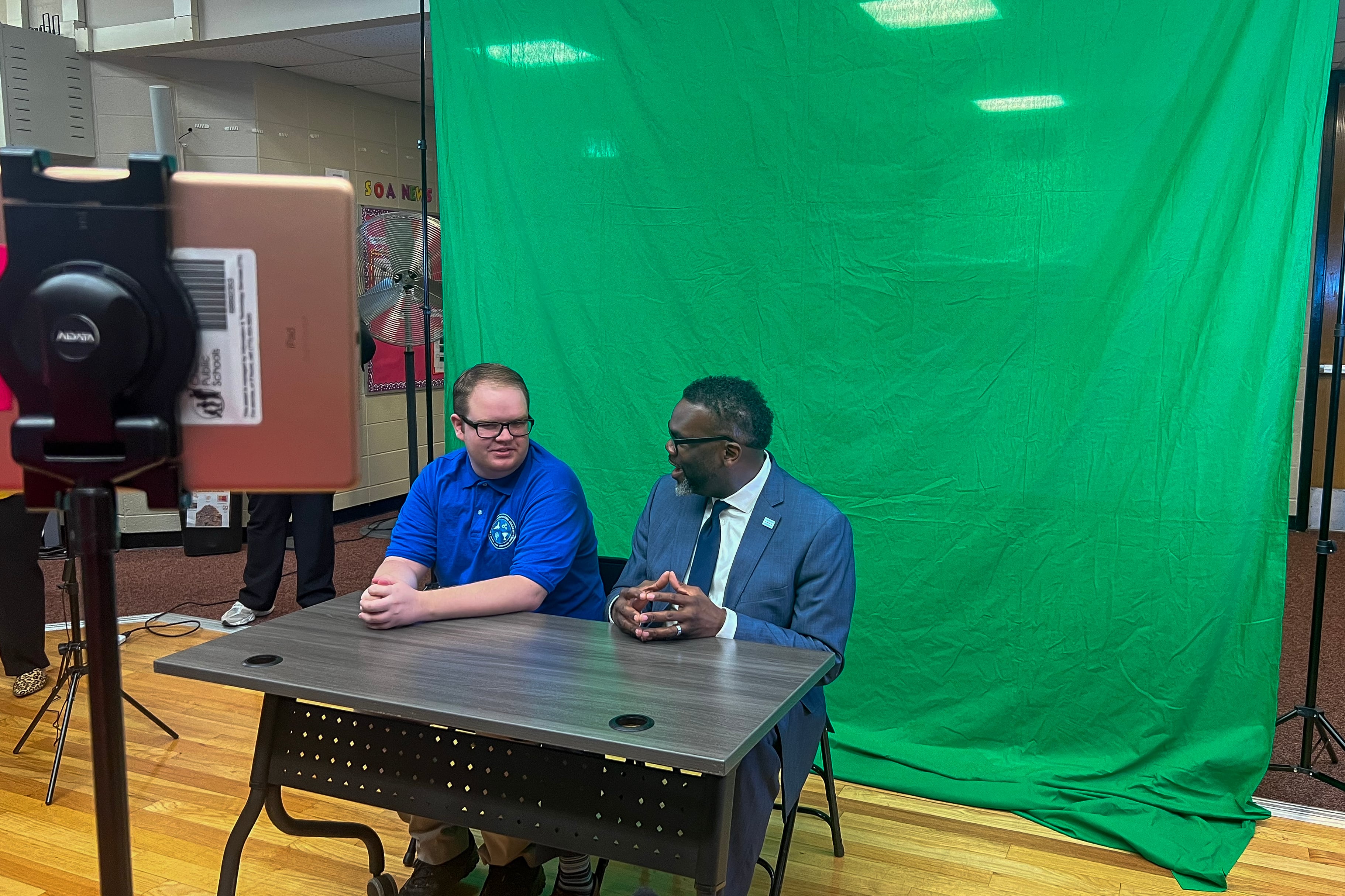 Mayor Brandon Johnson sits with Aidan Hughes at a mock broadcast studio at Southside Occupational Academy High School in Englewood. The school provides job training and life skills to older students with more challenging disabilities.