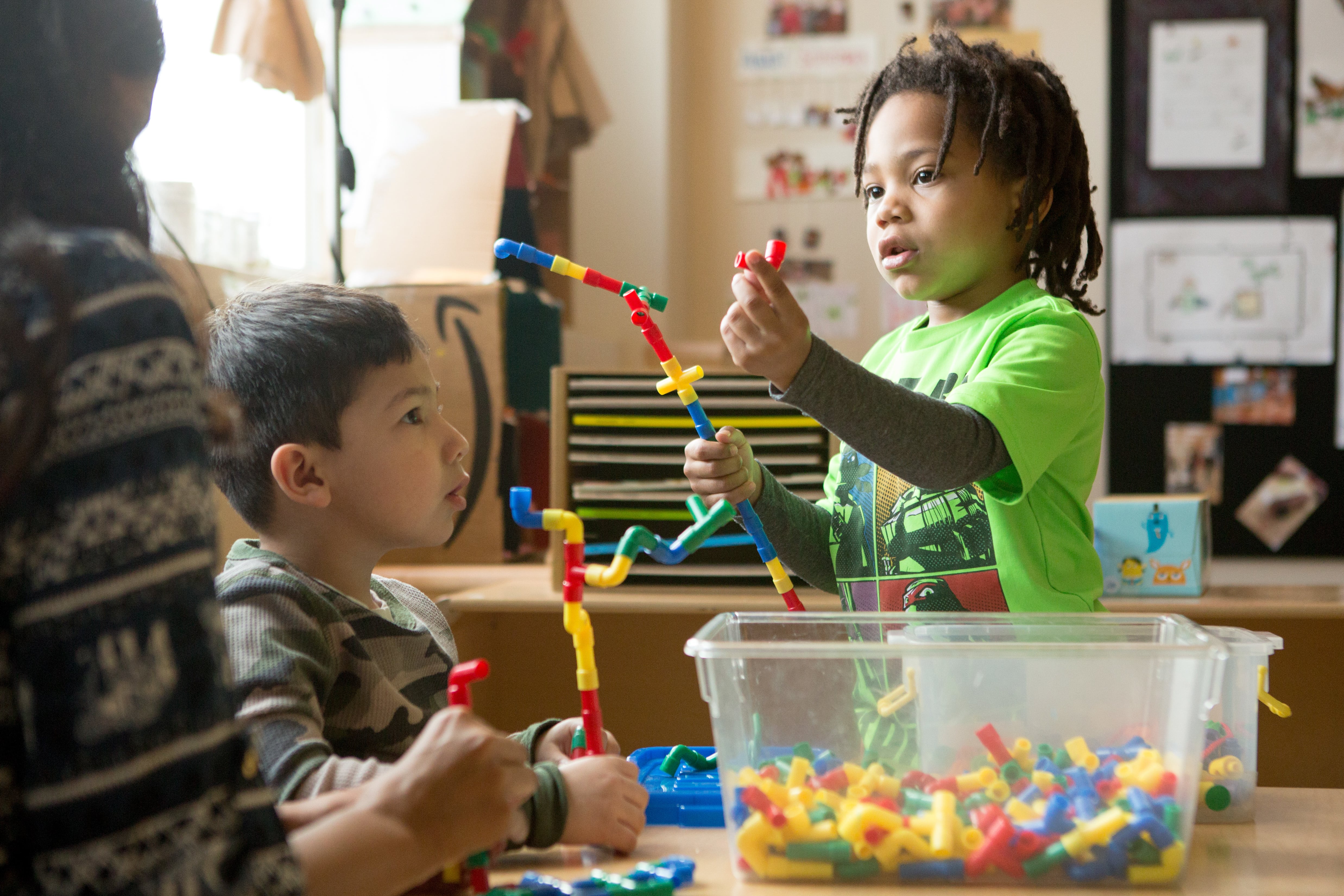 Two preschoolers play with colorful plastic building toys at a table.