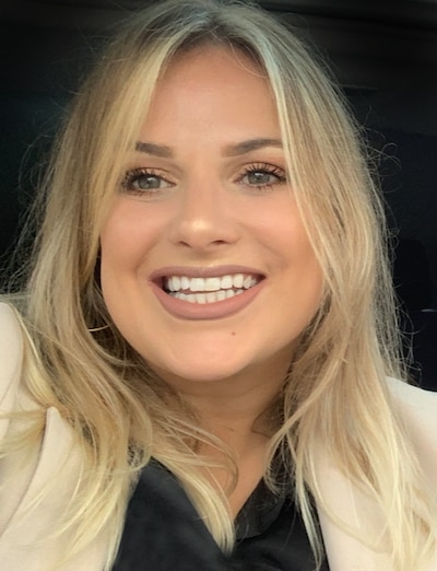 Headshot of blond wearing a black shirt and a tan blazer