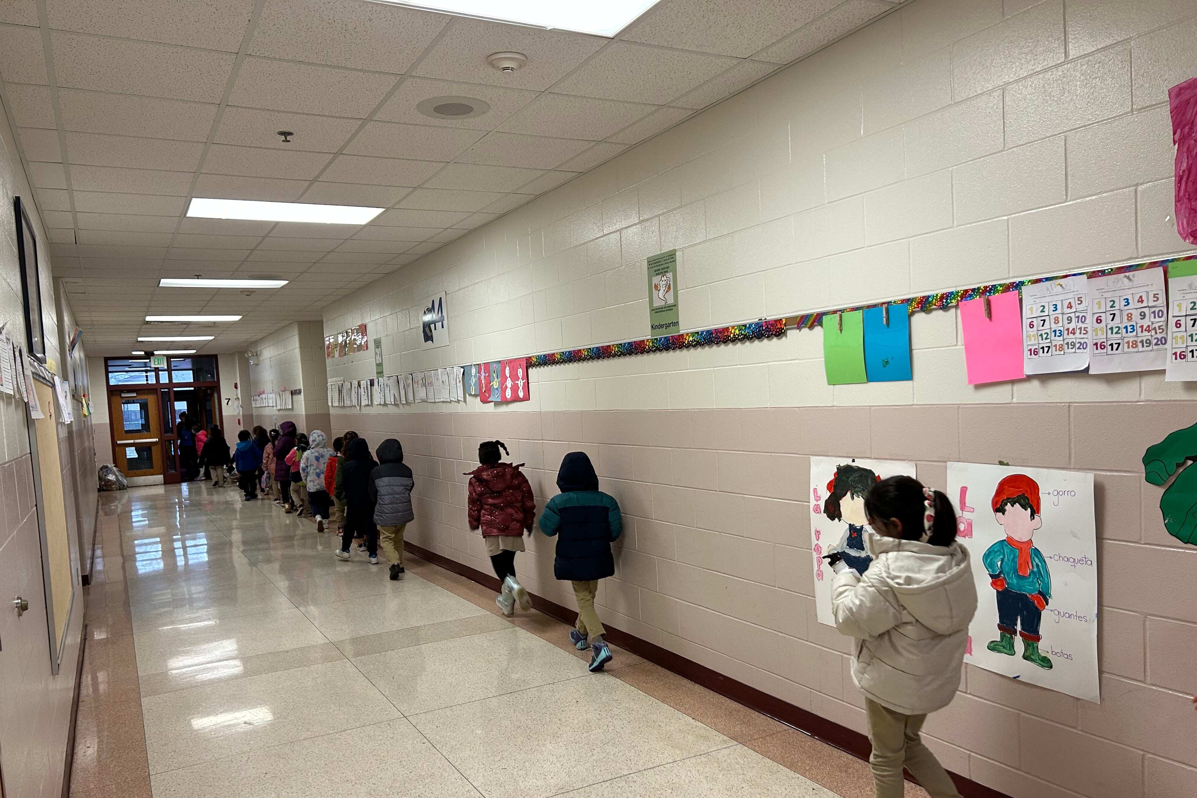 Students walk along the right side of a school hallway.