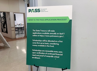 A green poster with white letters sits in a community center room.