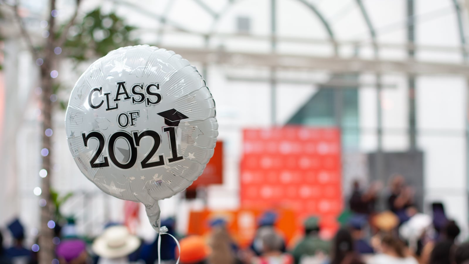 A balloon that reads “Class of 2021” floats in the audience of a graduation.