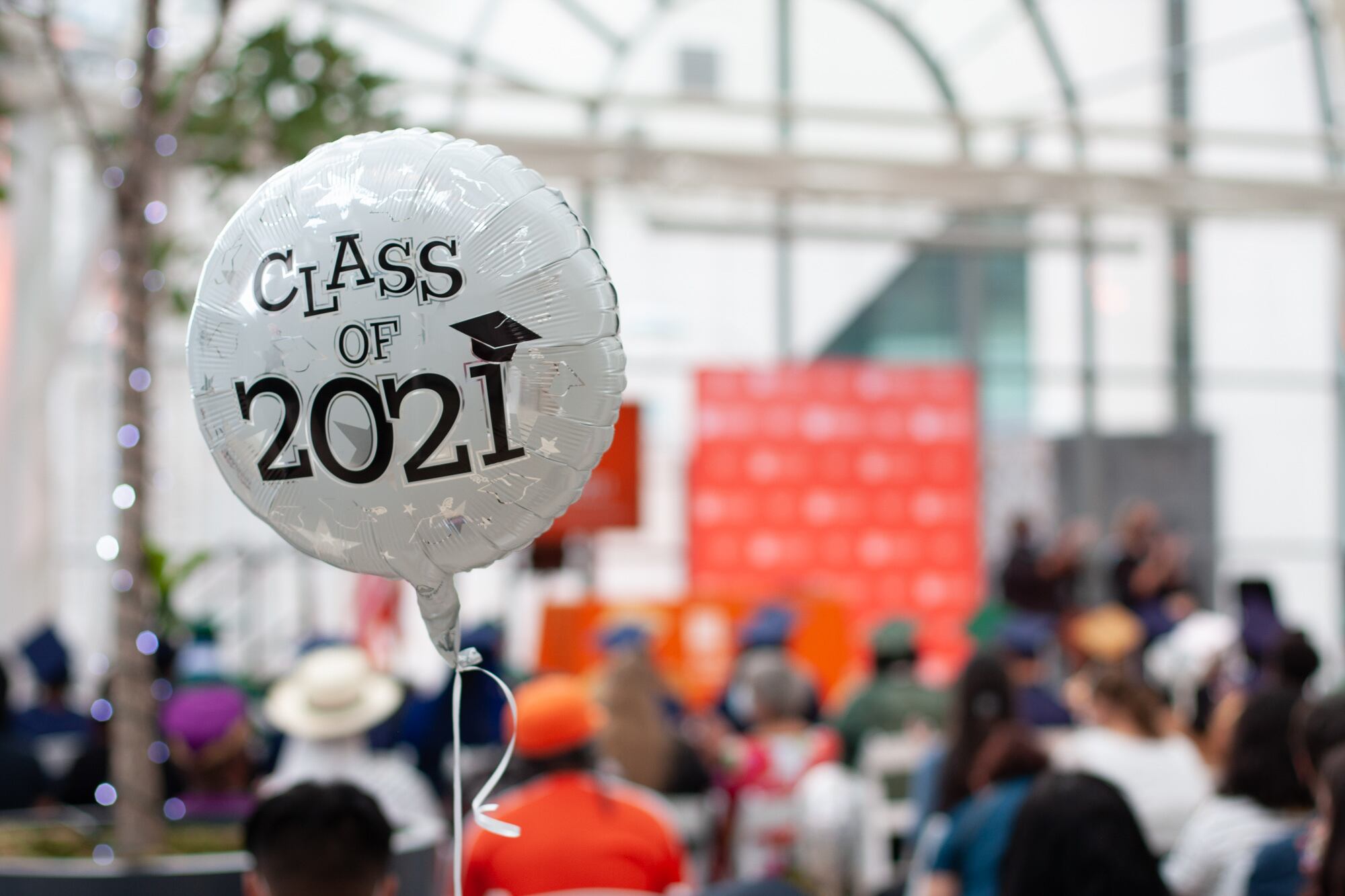 A balloon that reads “Class of 2021” floats in the audience of a graduation.