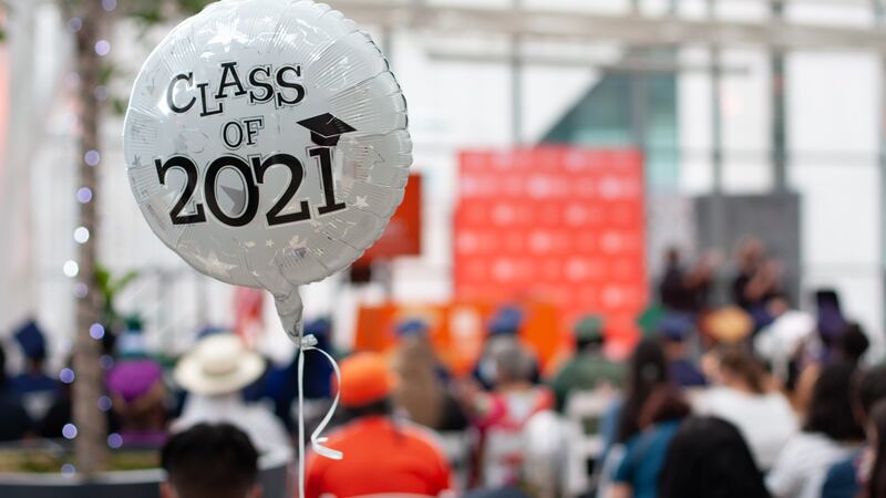 A balloon that reads “Class of 2021” floats in the audience of a graduation.