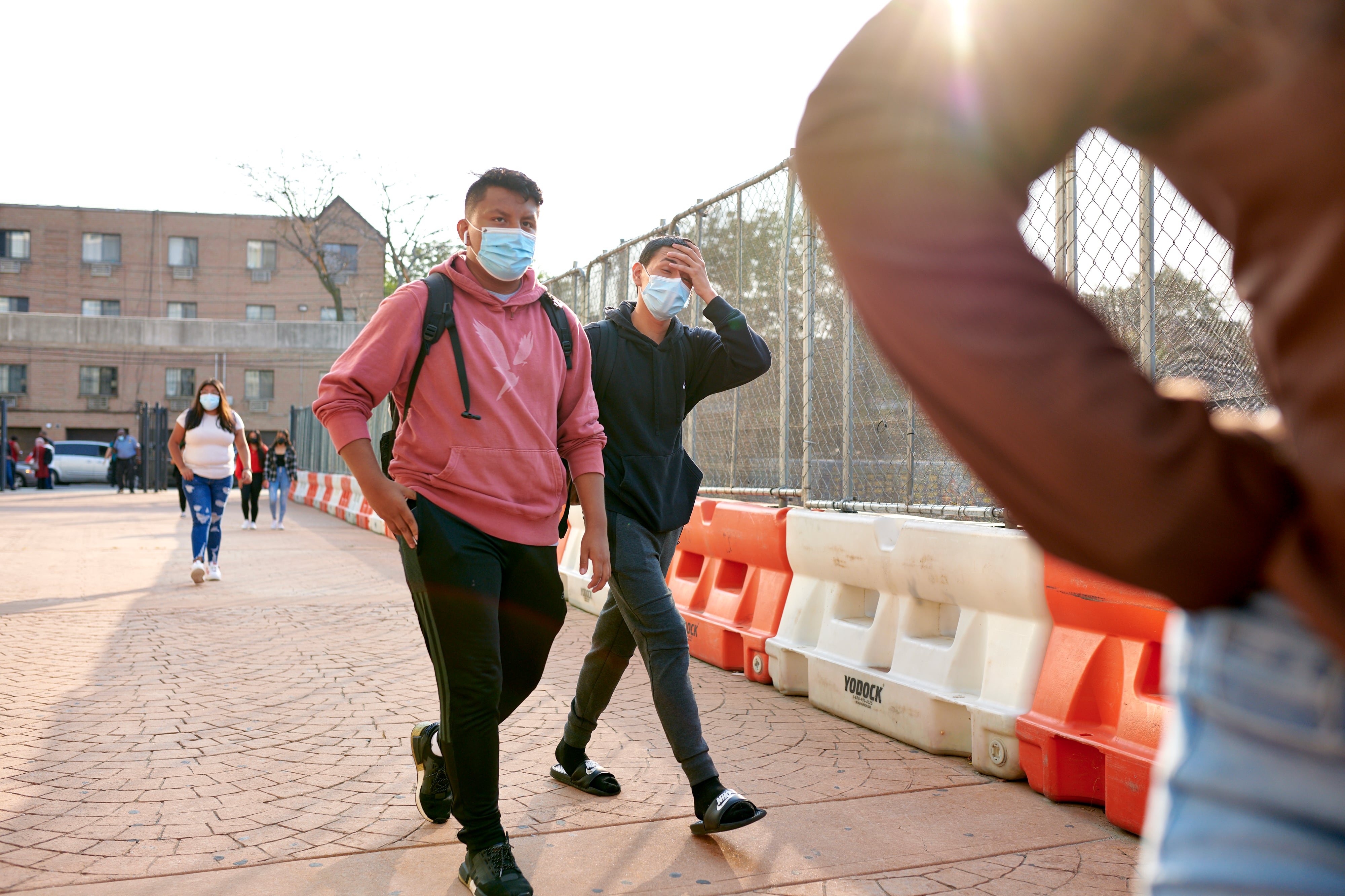 Two students are walking outside with masks on their faces.