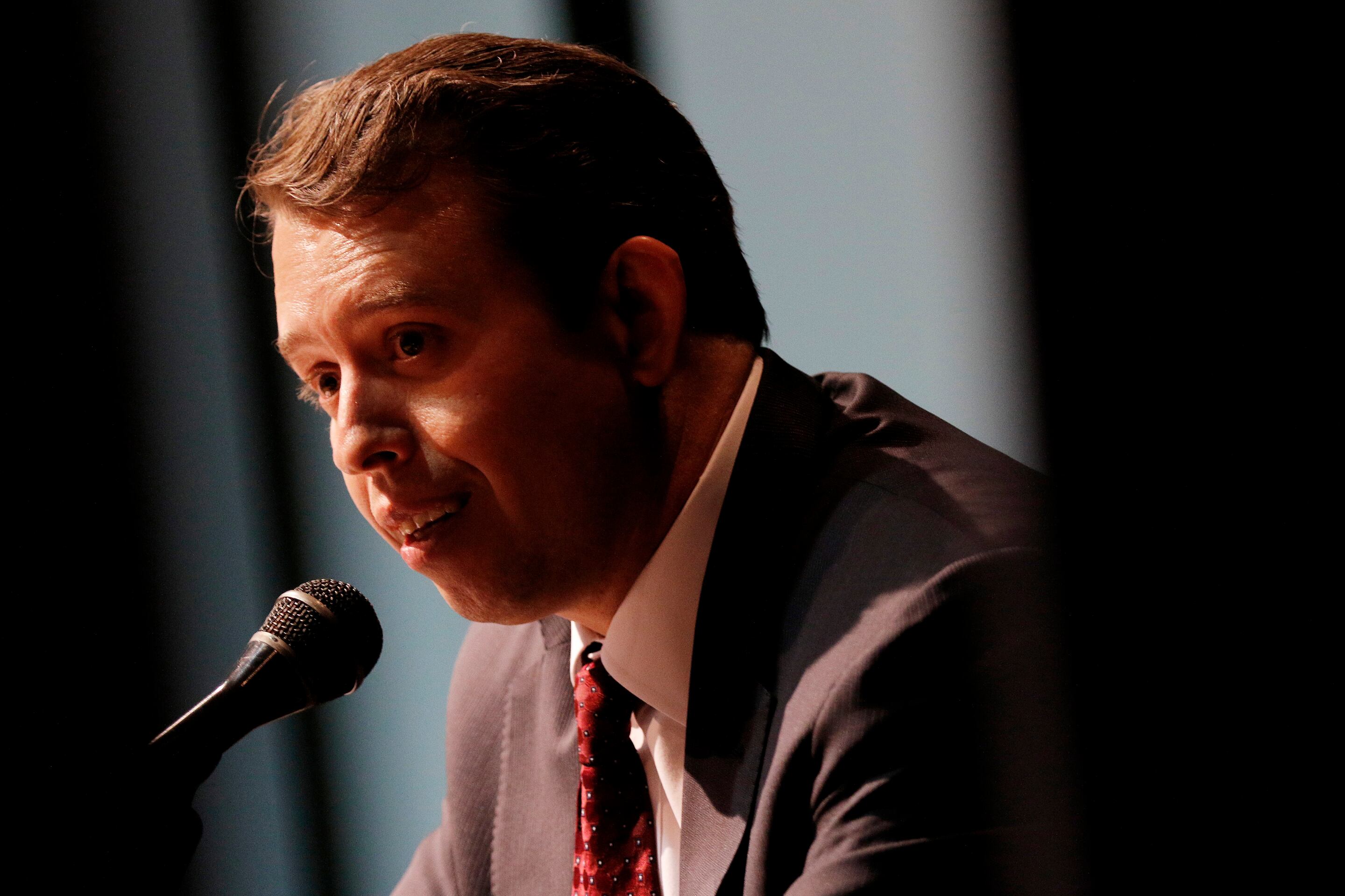 San Antonio Schools Superintendent Pedro Martinez, wearing a suit with a red tie, speaks into a microphone.