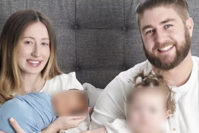 A woman with long hair and a man with a beard hold two young children, whose faces have been blurred.