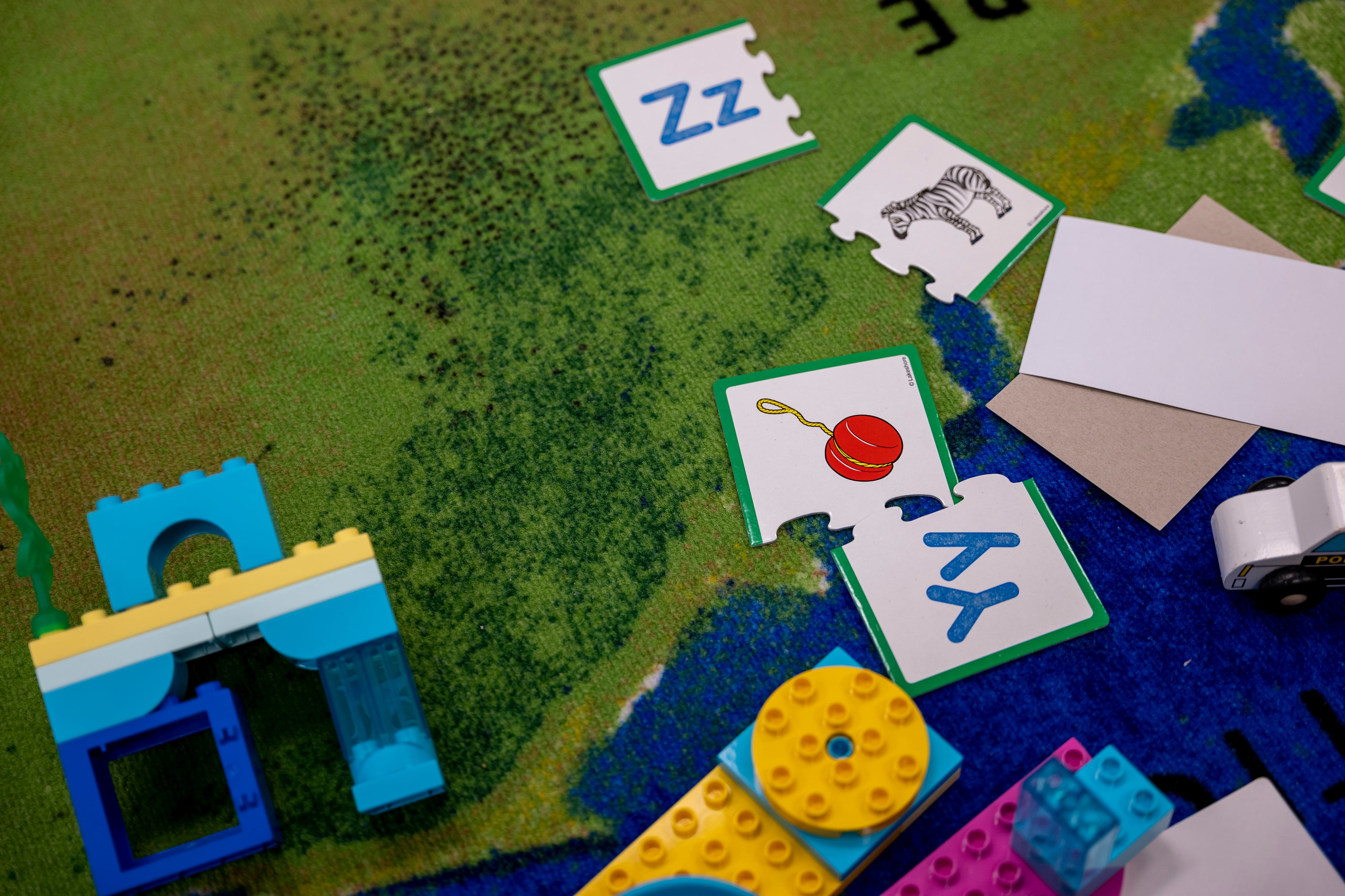 Puzzle pieces and legos are scattered on a colorful carpet.