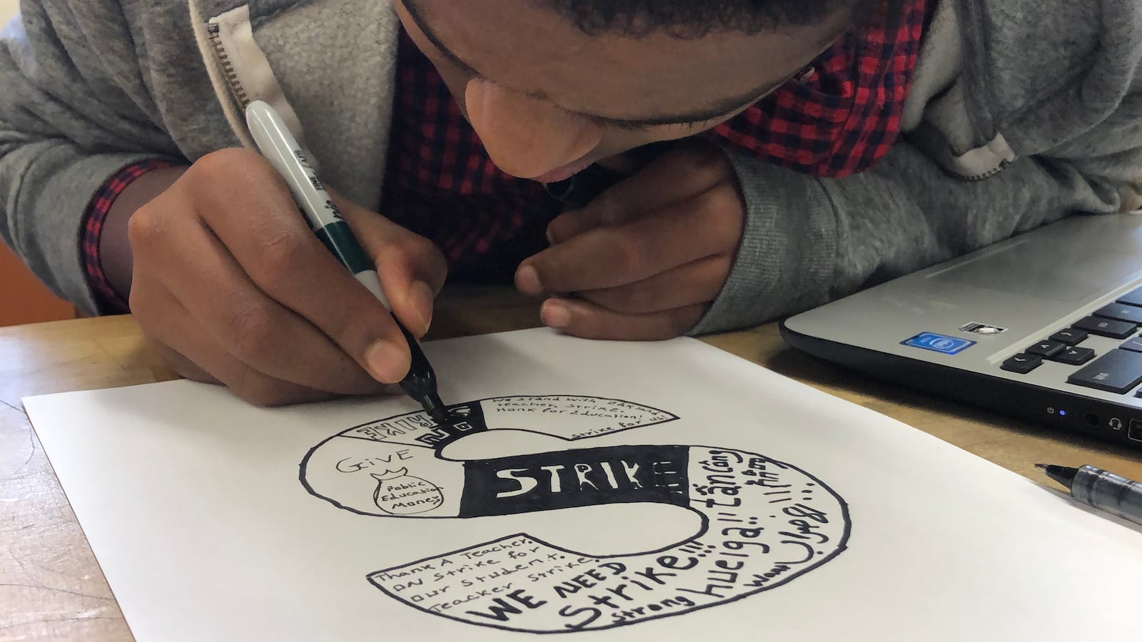A student at Oakland International High School works on a strike-related art project, part of a lesson in the February 2019 run-up to a planned teachers strike in the Oakland Unified School District.