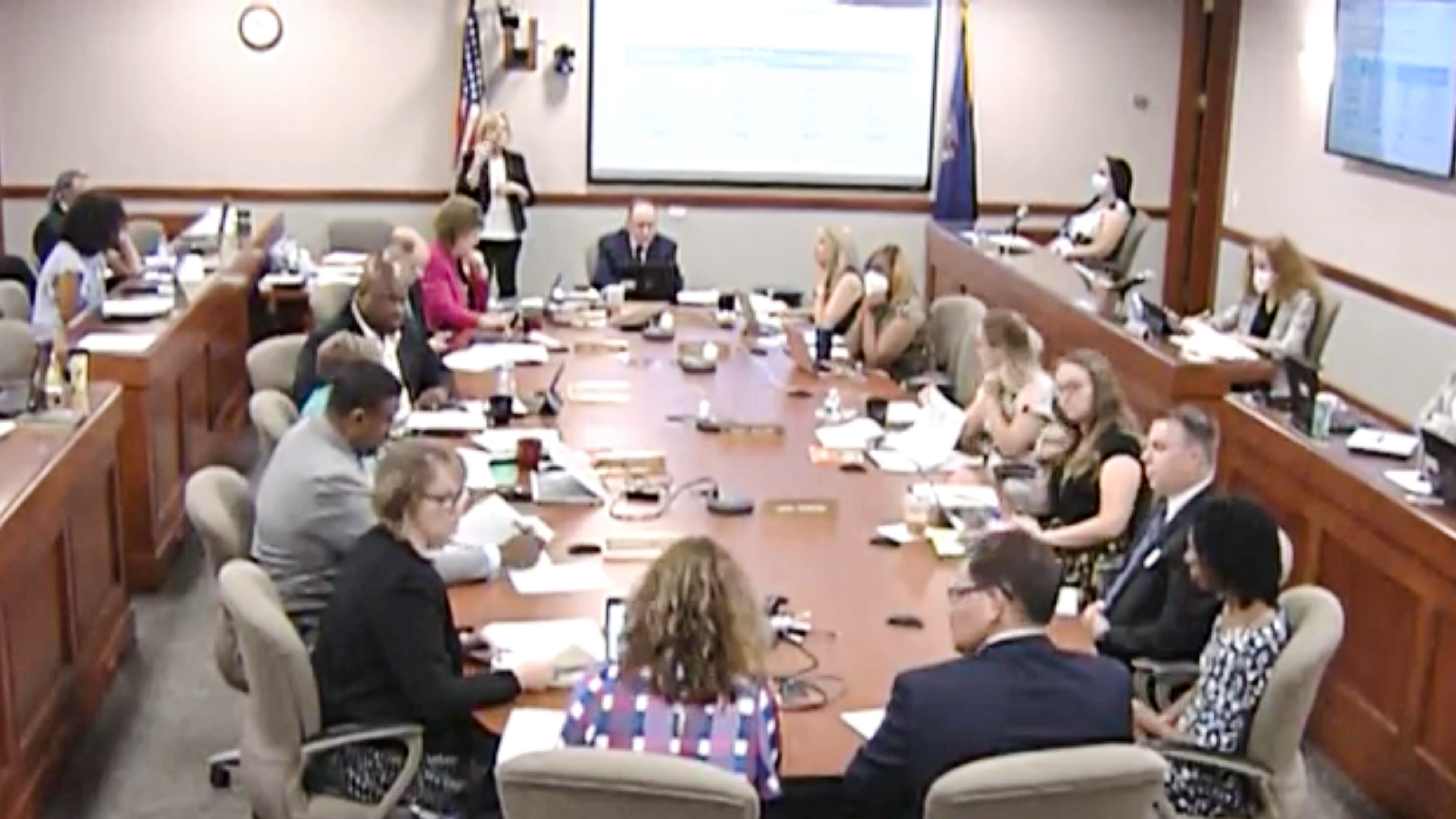 Michigan Board of Education members are joined by several other school officials seated around an oblong table in a windowless conference room in Lansing.
