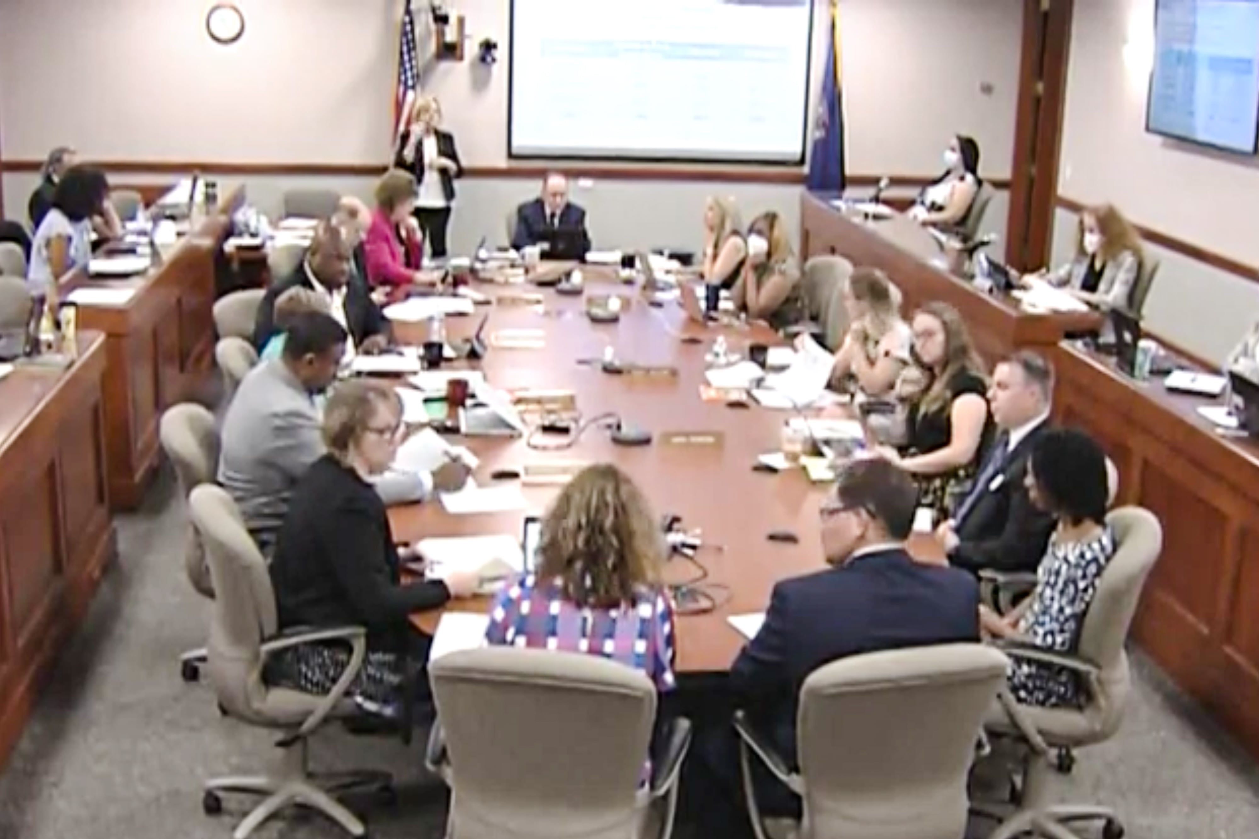 Michigan Board of Education members are joined by several other school officials seated around an oblong table in a windowless conference room in Lansing.