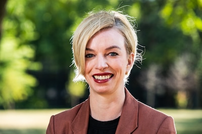 A woman with short hair and a brown jacket.