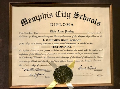 A wooden frame surround a high school diploma for Elvis Presley.