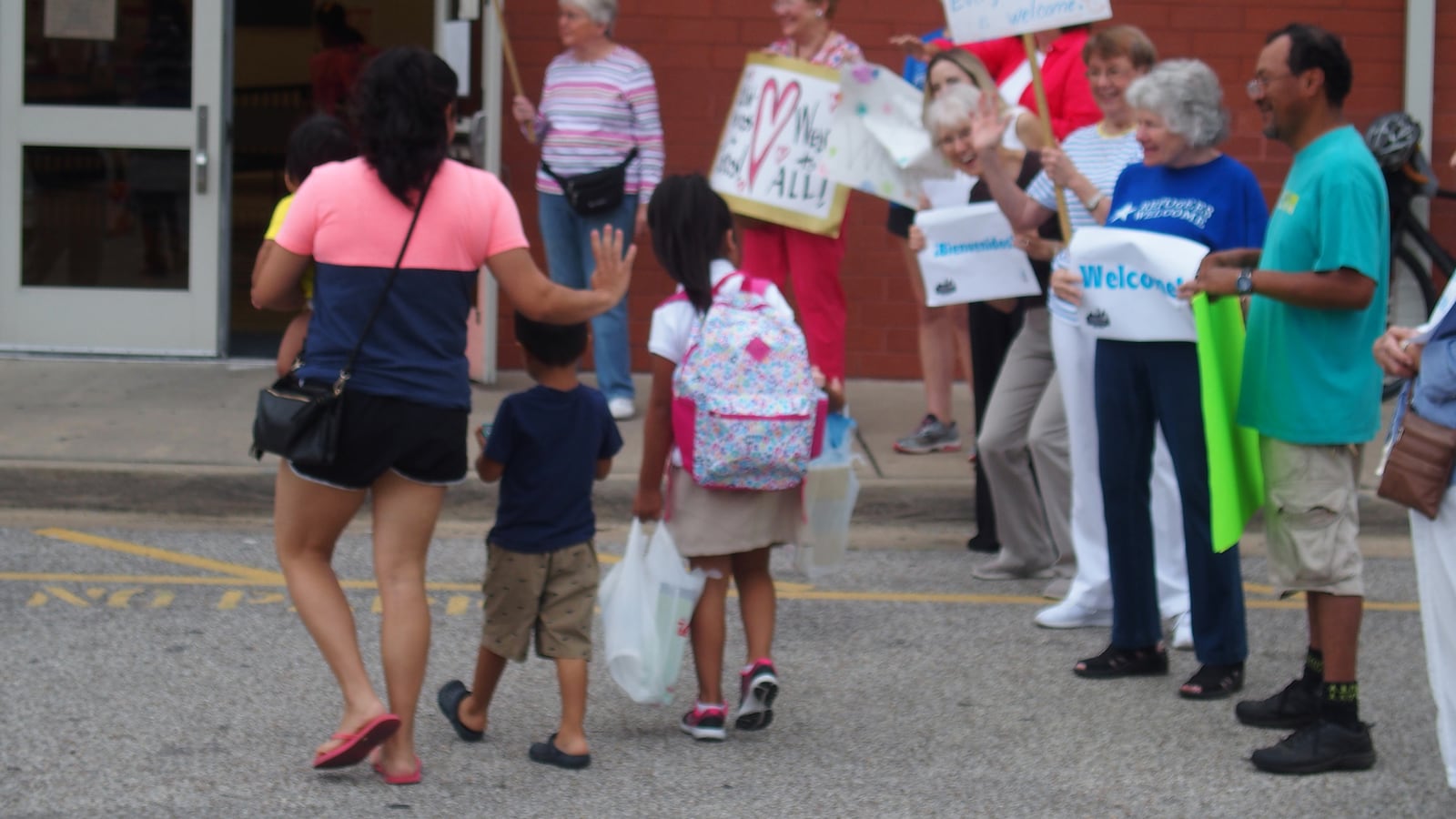 Neighbors, faith leaders and advocacy groups greet immigrant families arriving at Brewster Elementary School on the first day of class in Memphis.