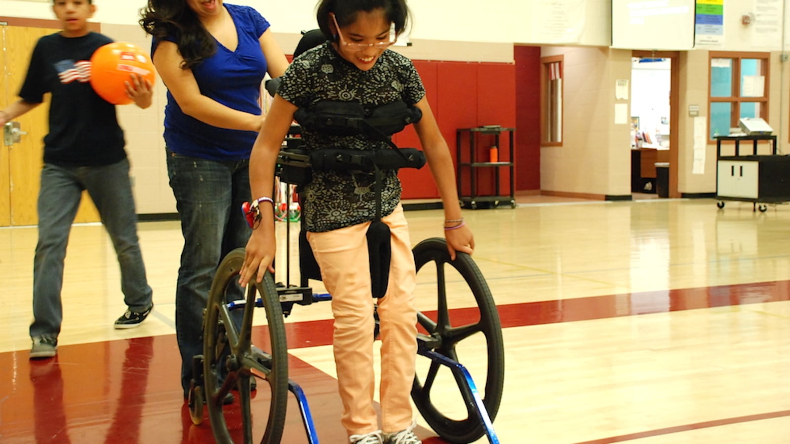 Gabi, a student at Bruce Randolph School, works with a paraprofessional during a recent adapted physical education class there.