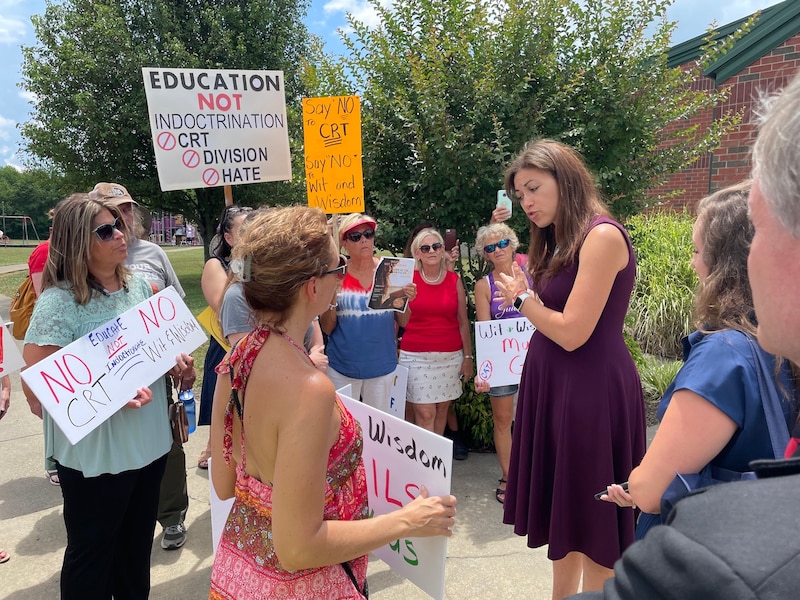 State Commissioner of Education Penny Schwinn talks to a small group of about a dozen protestors outside near a school.