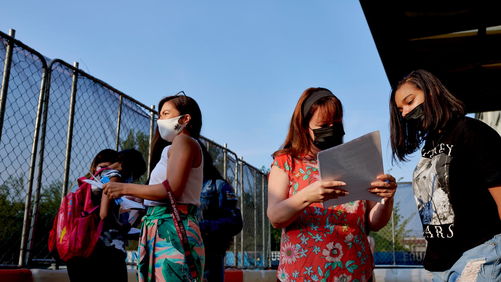 Faculty and staff assist Pan American High School students complete COVID screening forms before classes begin.