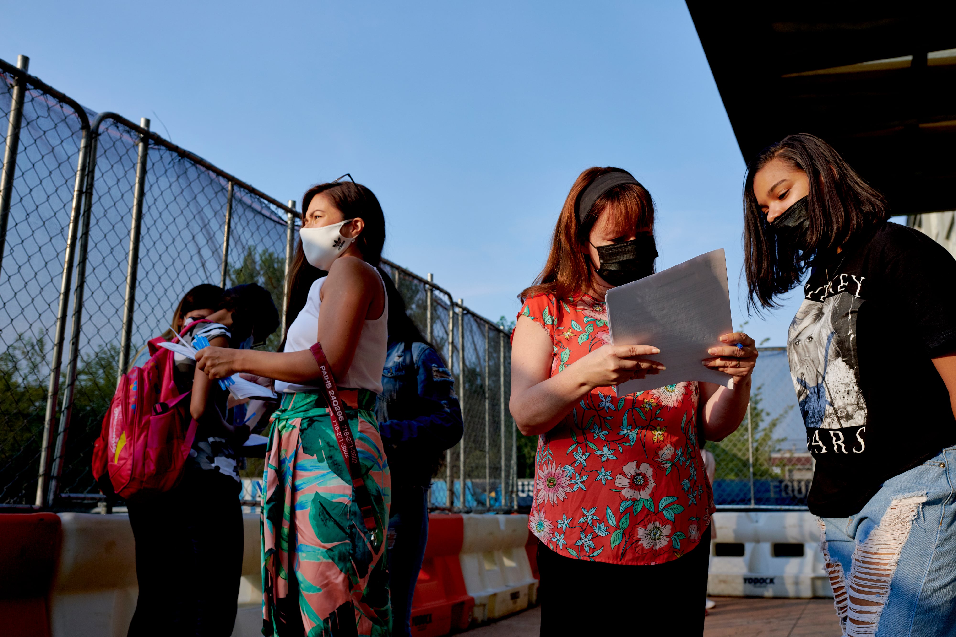 Faculty and staff assist Pan American High School students complete COVID screening forms before classes begin.