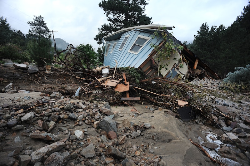 A mangled house sits among debris.