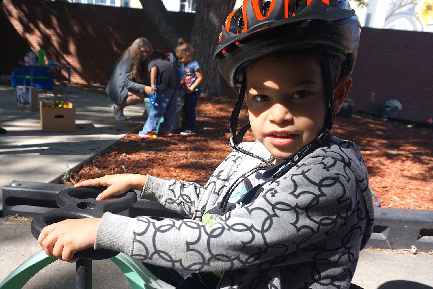 A boy rides a tricycle on the playground of the preschool at Laradon in north Denver.
