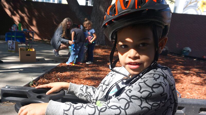 A boy rides a tricycle on the playground of the preschool at Laradon in north Denver.
