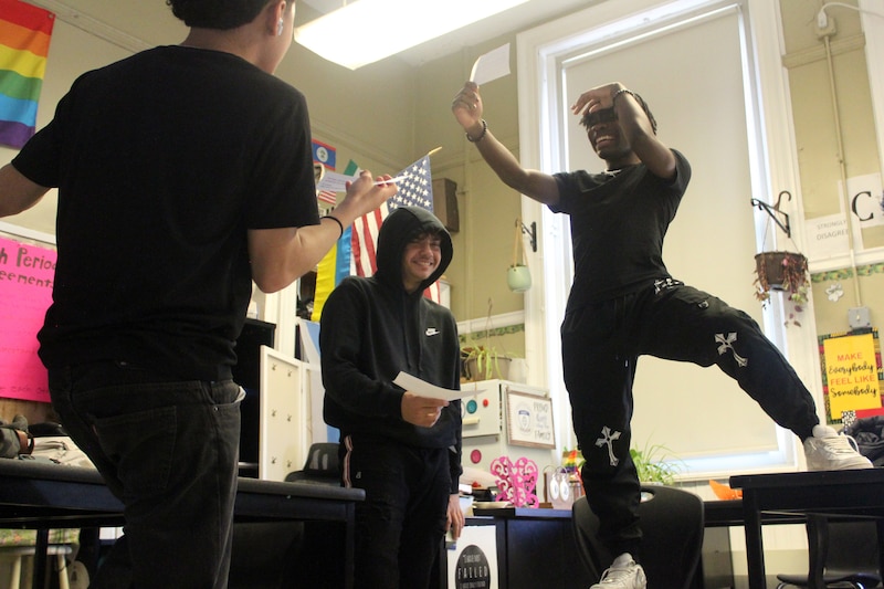 Three students practice their monologues in a classroom.
