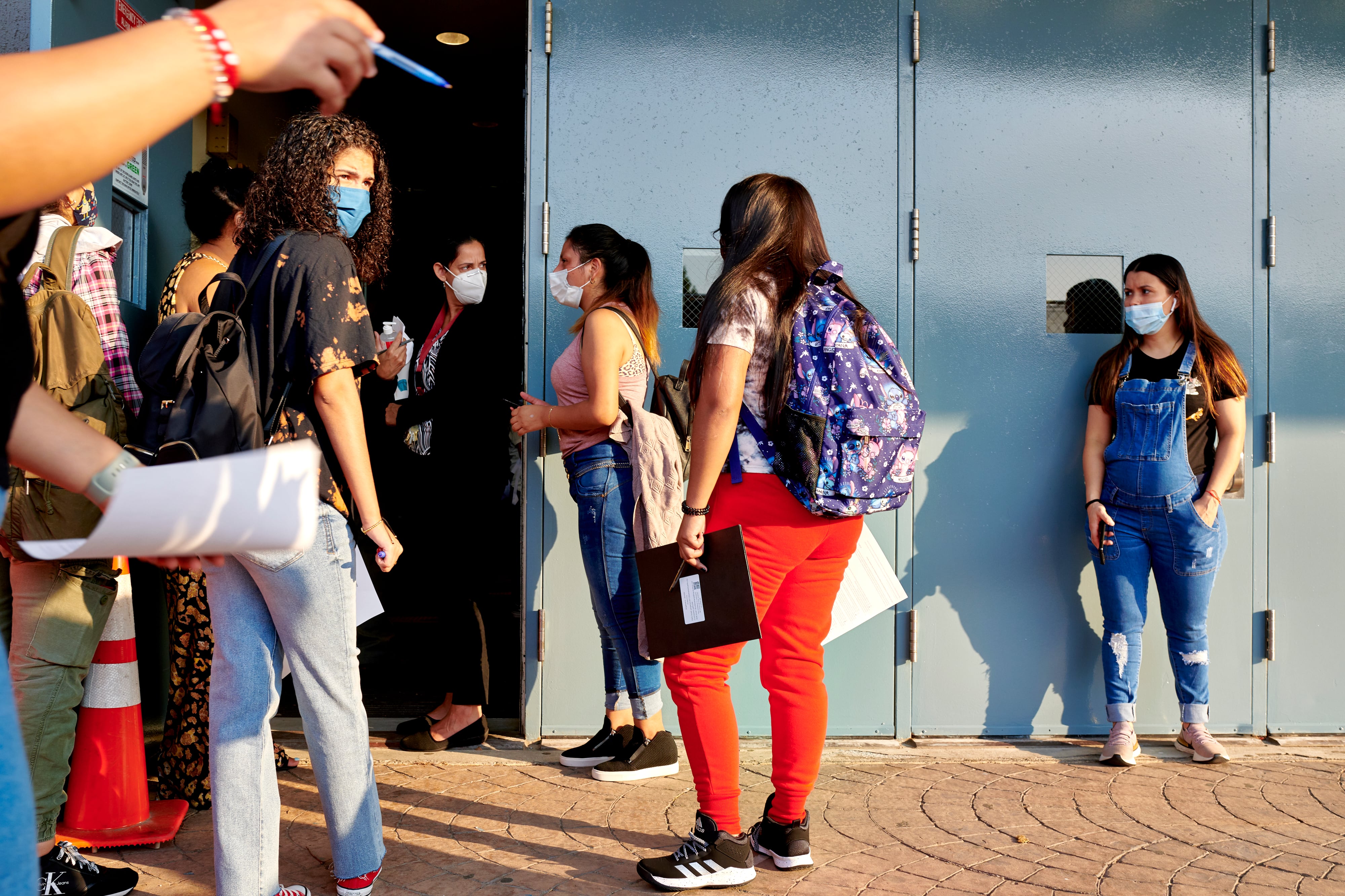 Students wait to enter the blue doors of their high school as faculty direct them on the first day of classes.