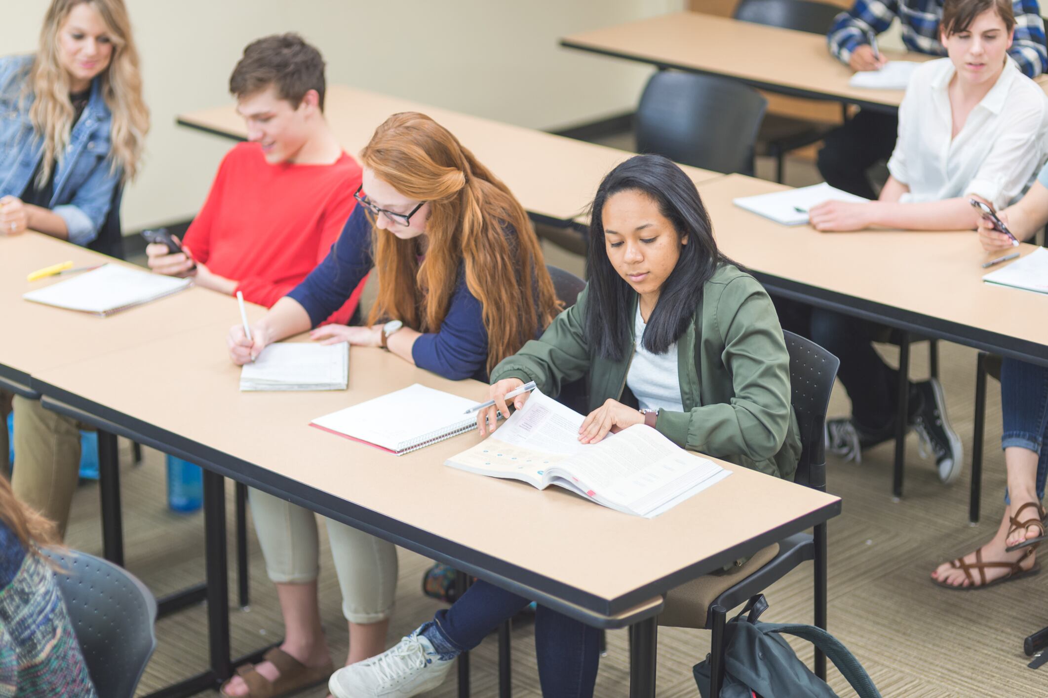 Students sit at desks with paper and pencils