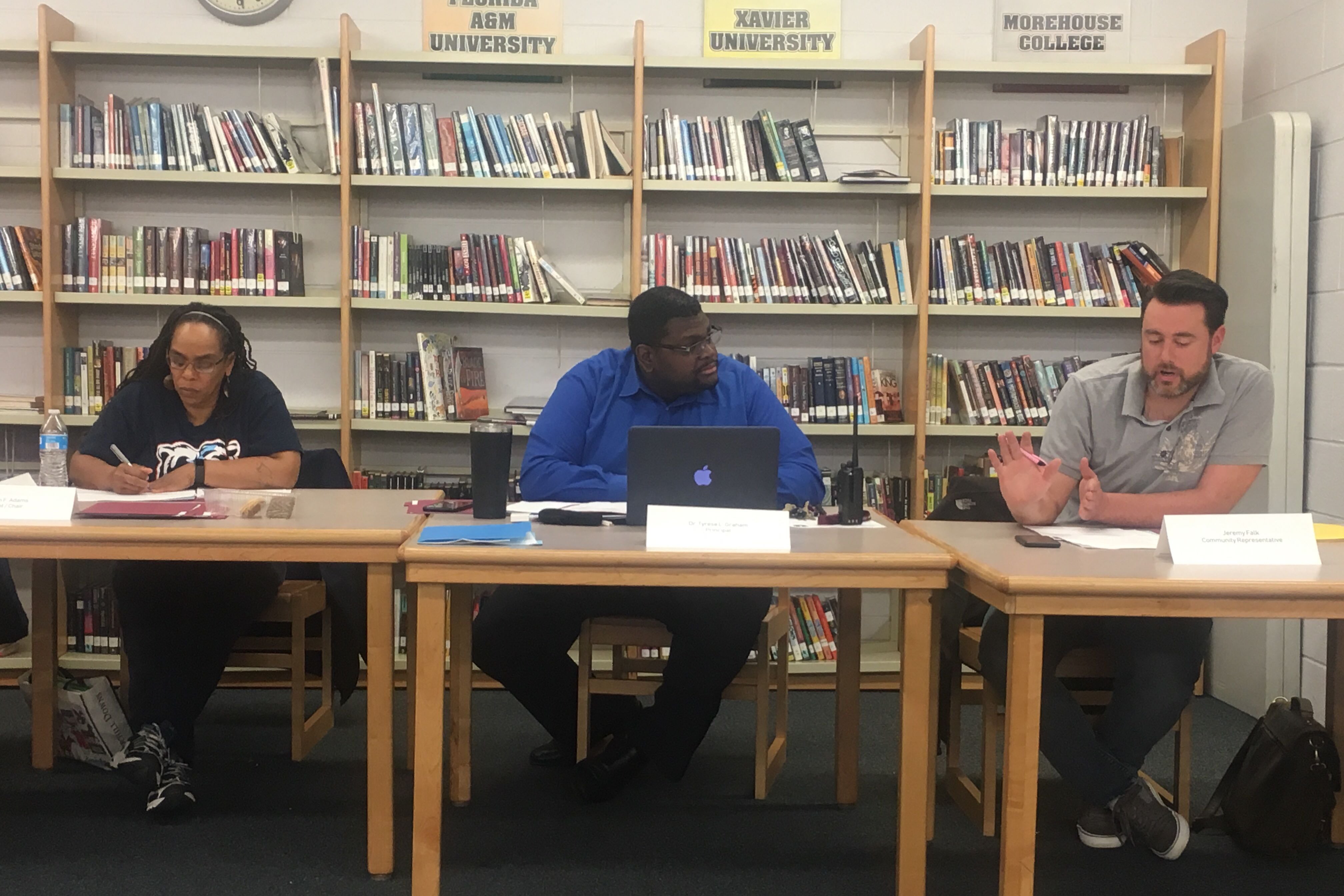 Three people sit at tables in a school library during a meeting in Chicago.