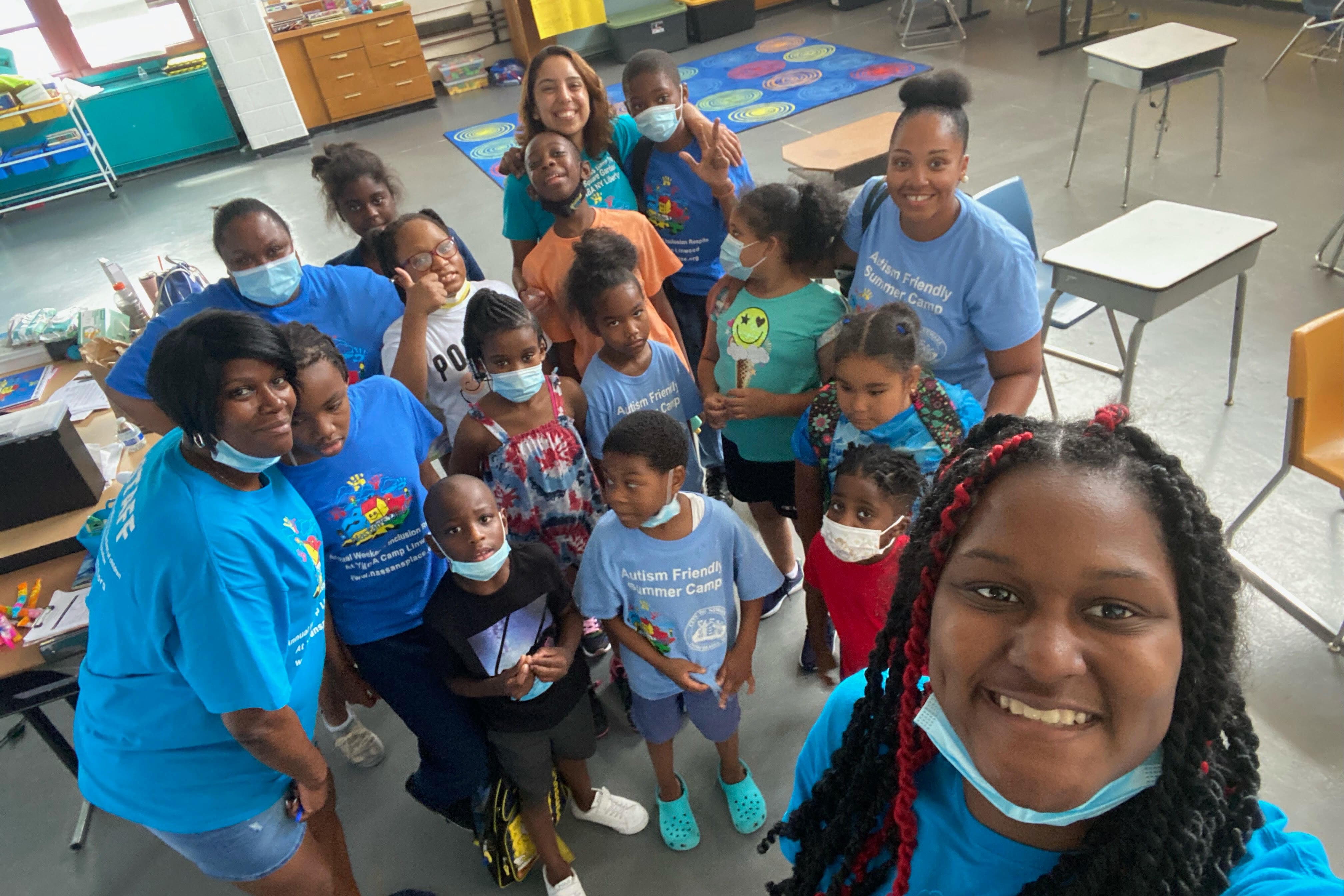 Five women pose with a group of school-aged children at a Newark summer camp for autistic children.