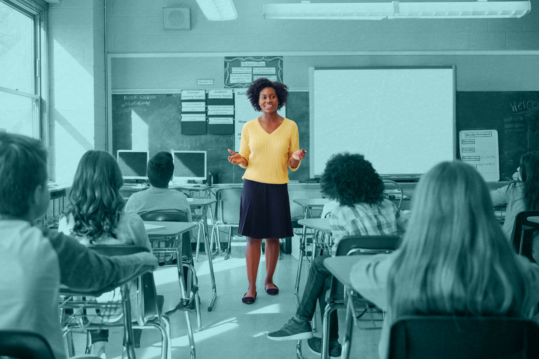 A new teacher standing at the front of her first class of sixth grade students.
