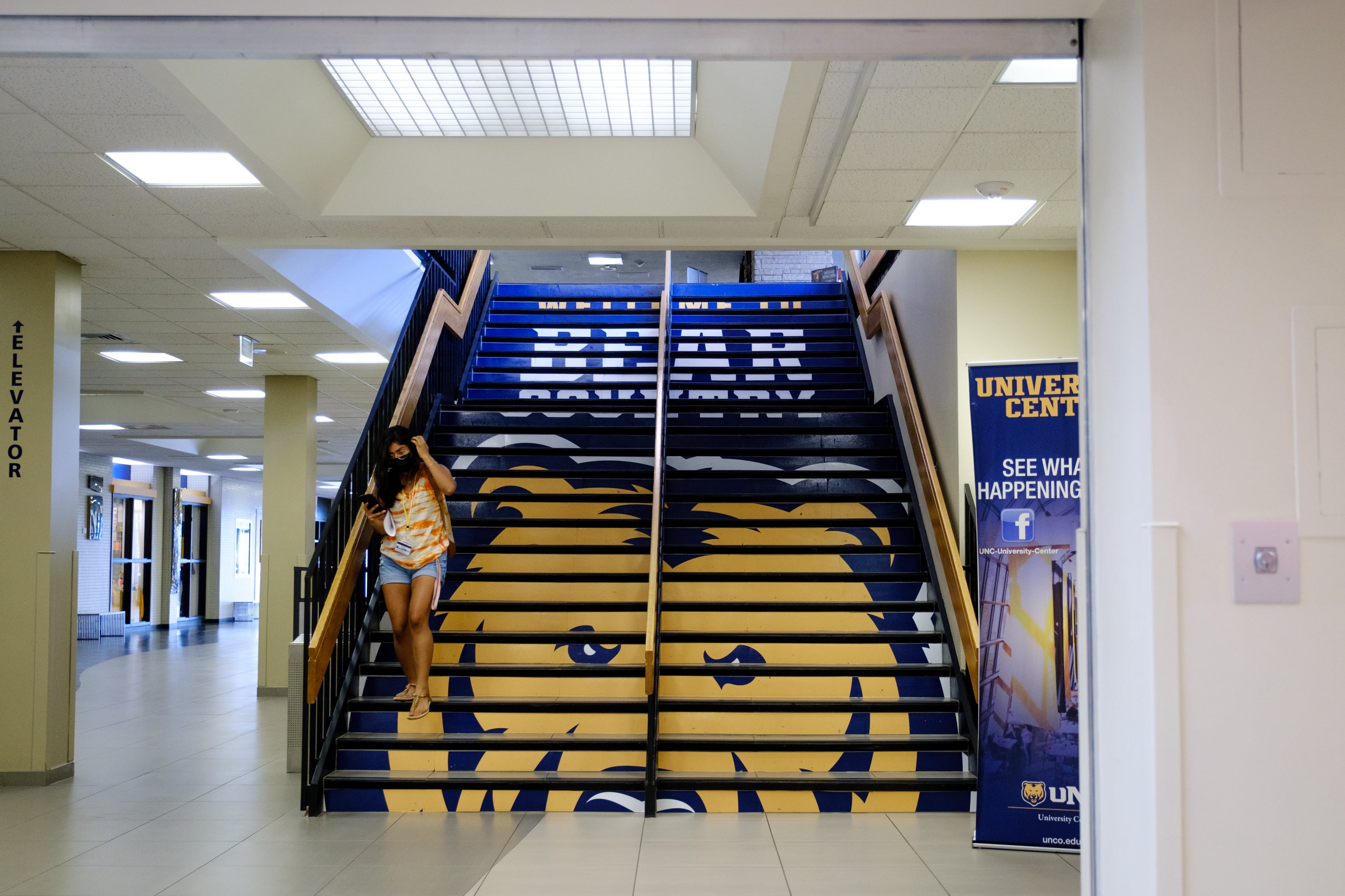 A student walks down a set of stairs with a bear painted on the stairs.