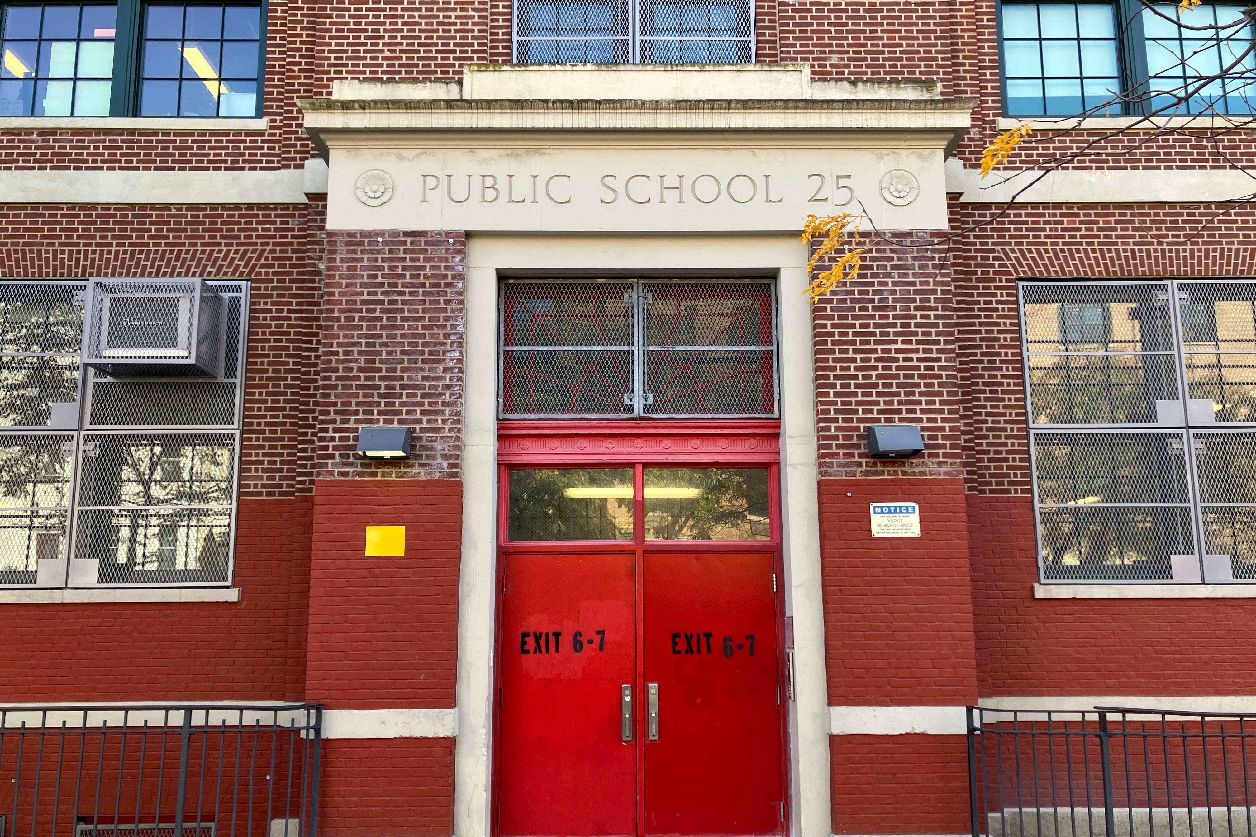 A large red front door on a red brick school building.
