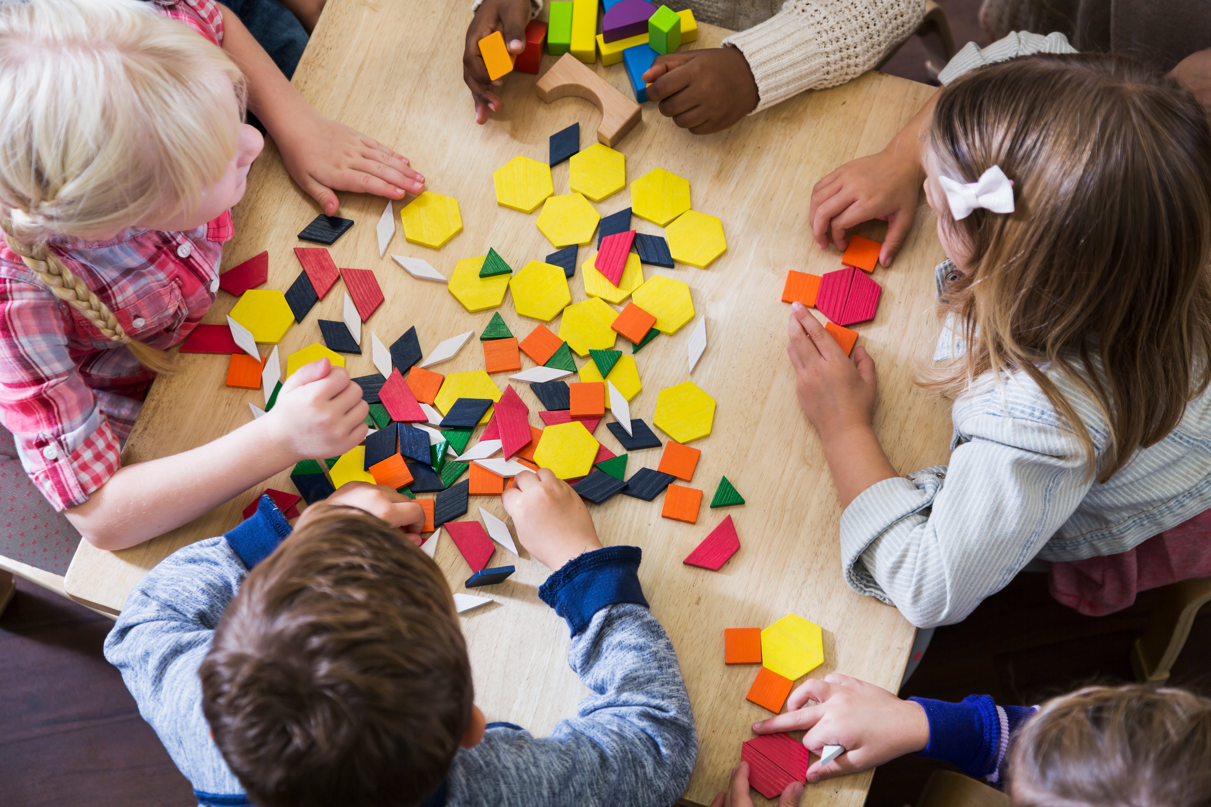 Children play with blocks and shapes, photographed from above.