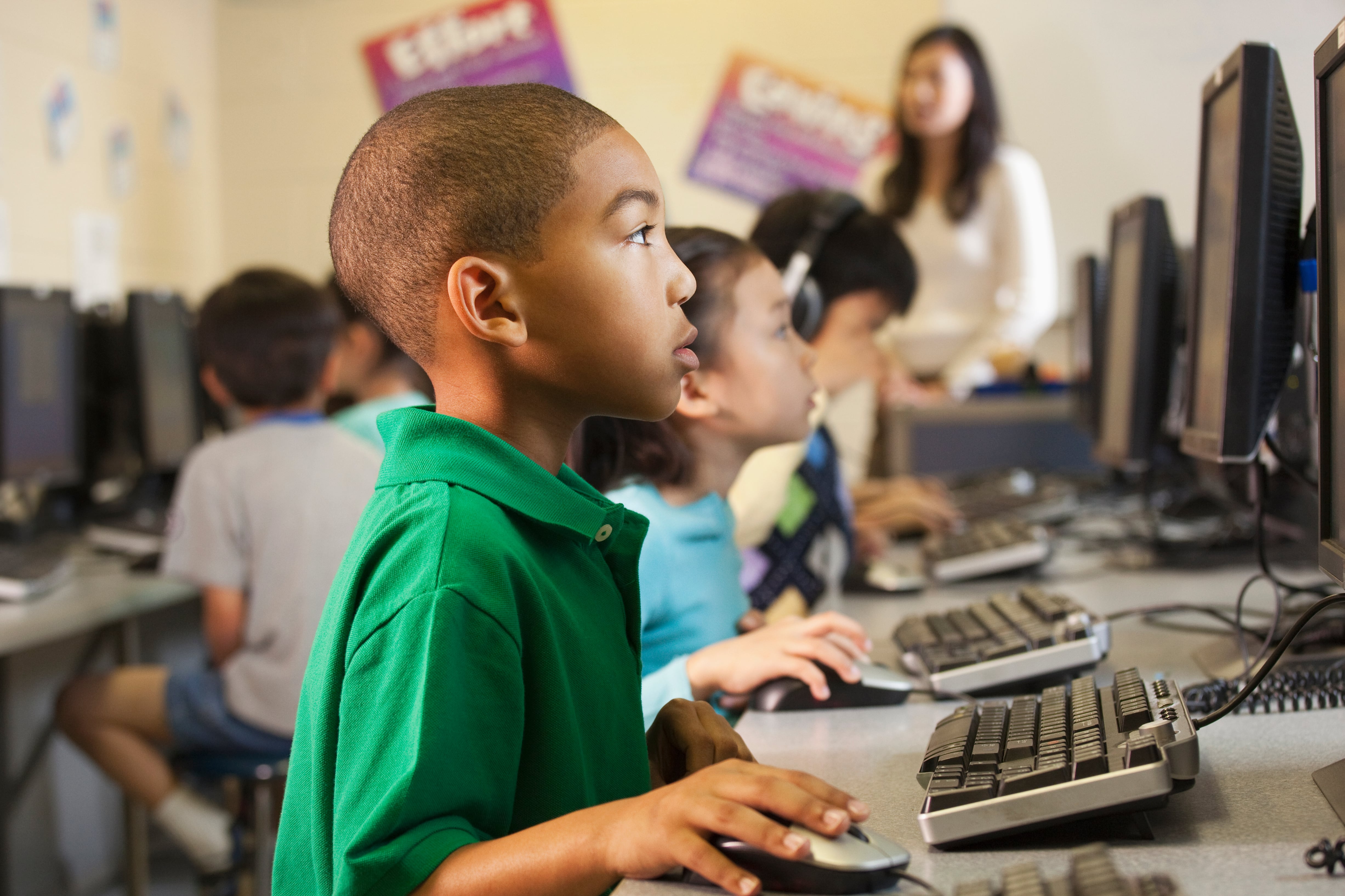 A boy in green looks at a computer screen.