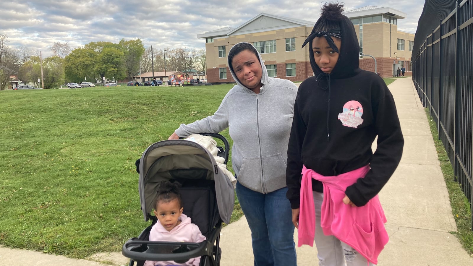 A parent and her two children stand outside a Detroit elementary school.