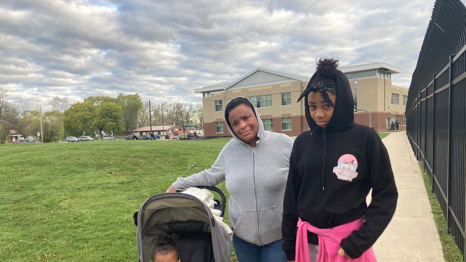 A parent and her two children stand outside a Detroit elementary school.