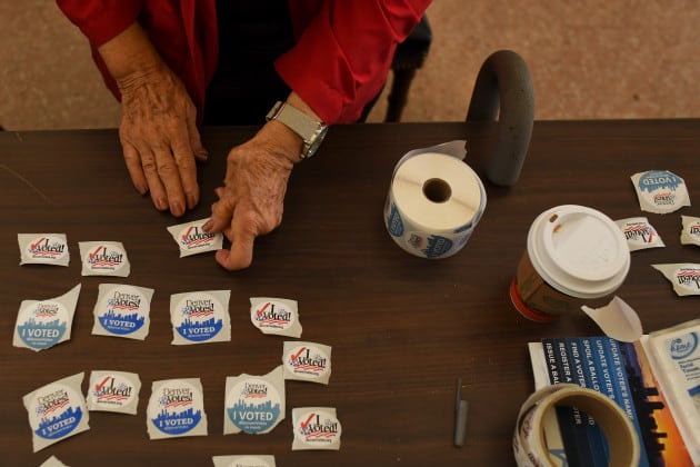 An election judge sets out voting stickers on a table.