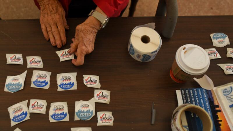 An election judge sets out voting stickers on a table.