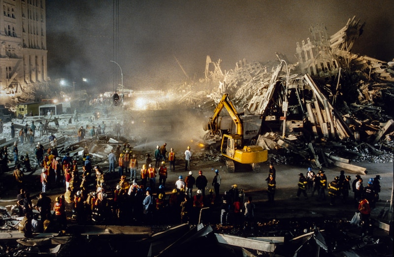 Emergency personnel work at night at a scene of devastation.